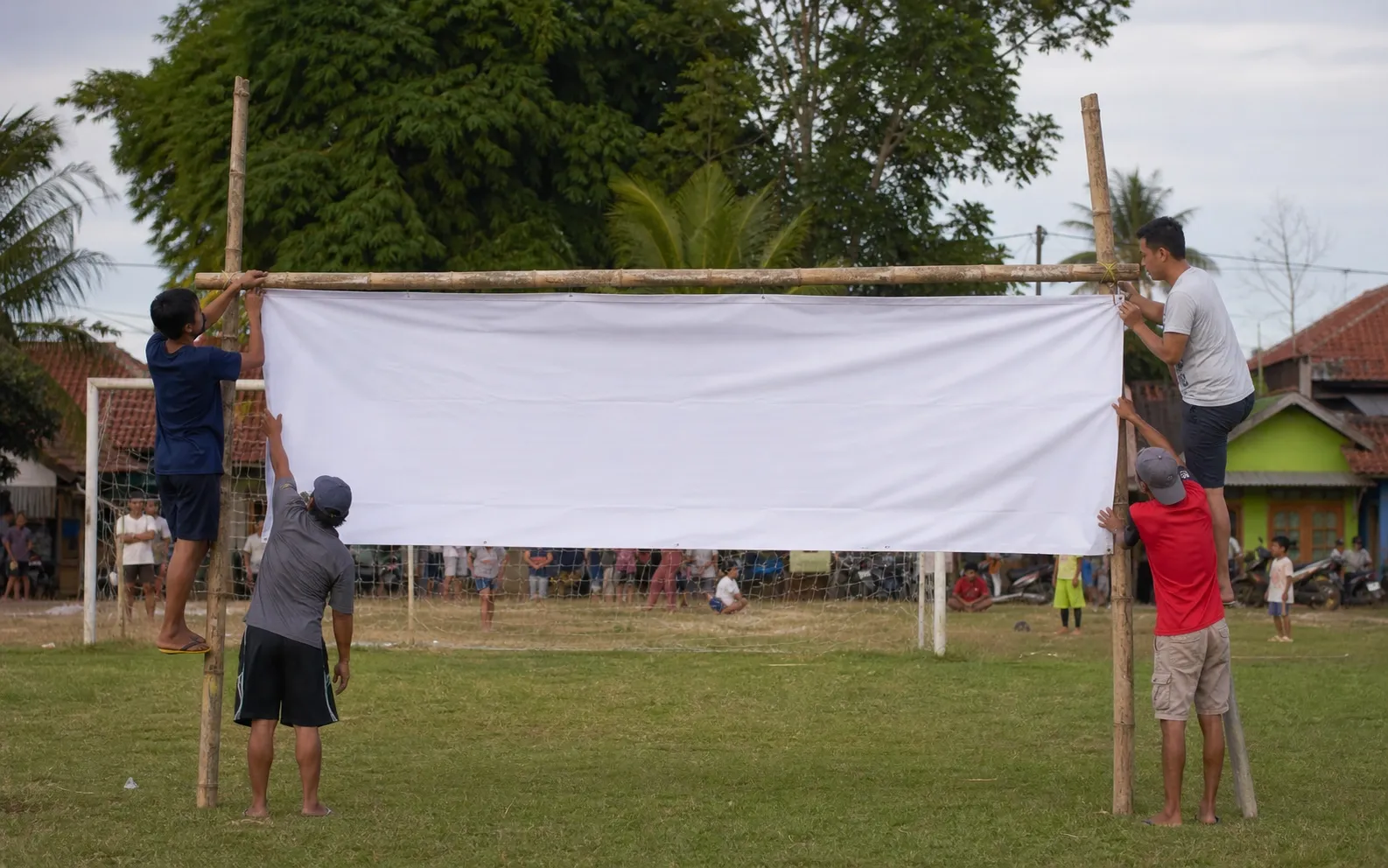 Relawan komunitas menyiapkan lapangan turnamen tanpa spanduk bertulisan